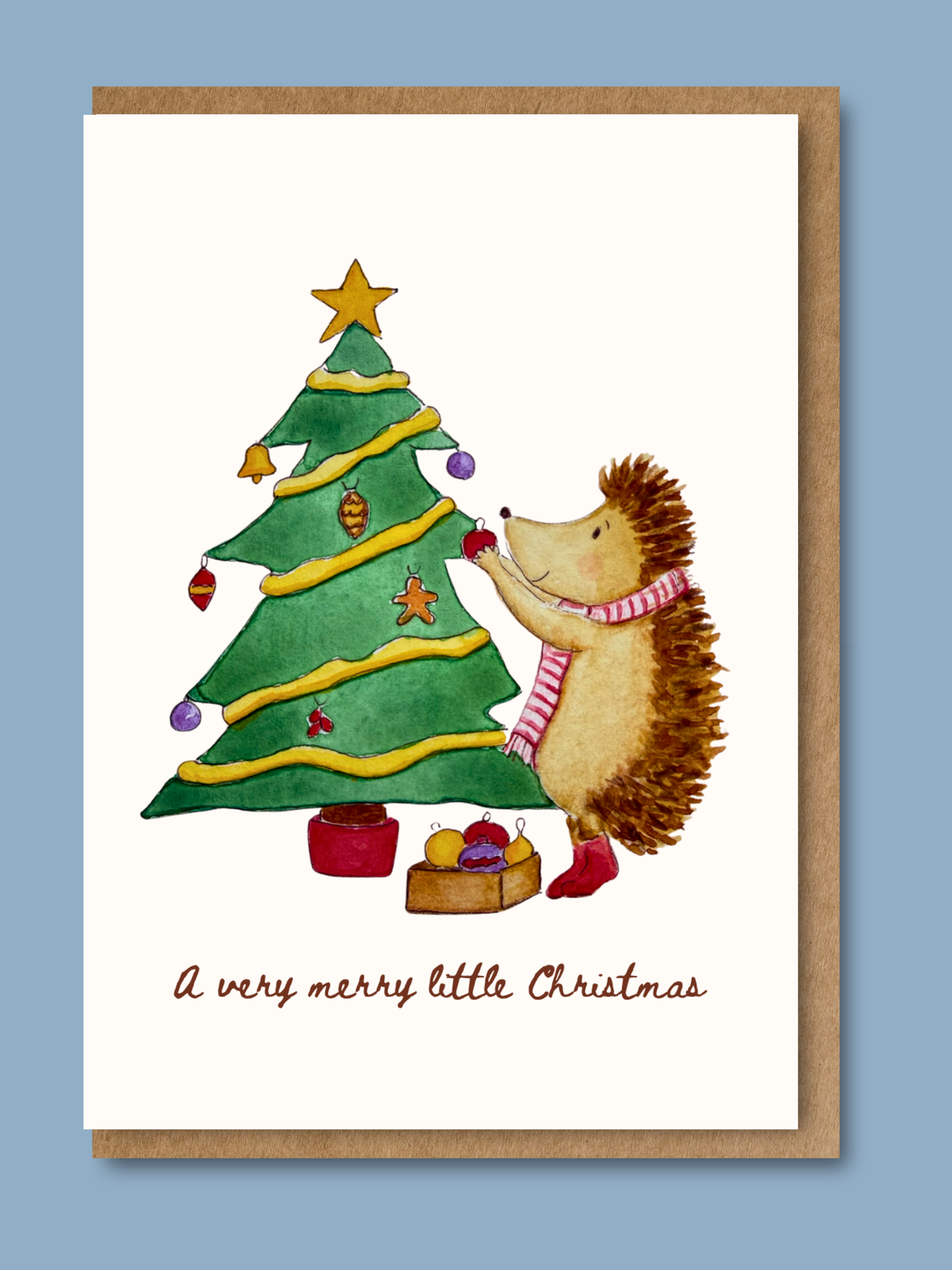 Christmas card with hand-illustrated watercolour hedgehog decorating a Christmas tree