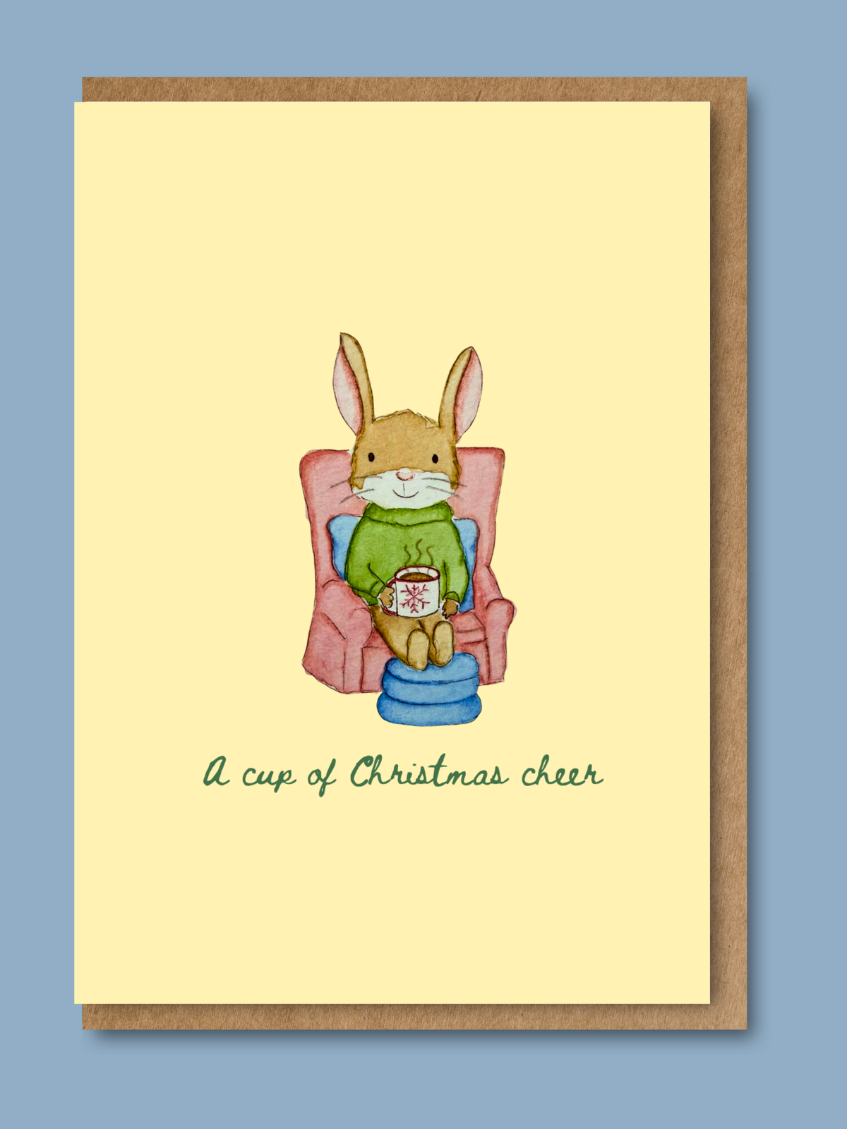 Christmas card with hand-illustrated watercolour rabbit holding a festive drink in an armchair